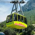 a yellow and green cable car in front of a mountain