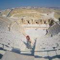 a woman standing in an amphitheater with a view