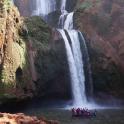a group of people in a boat in front of a waterfall