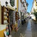a narrow street with a shop on the side of a building