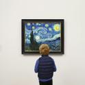 a young boy looking at a painting in a museum