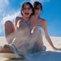 two girls sitting in the sand on the beach