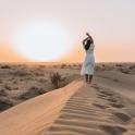 a woman standing on a sand dune in the desert