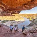 a group of people walking through a cave near a river
