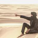 一名男子坐在沙漠沙丘上