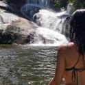 a woman in a bikini standing in front of a waterfall