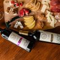two bottles of wine on a table with cheese and fruit