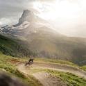 a person riding a bike on a dirt road in front of a mountain
