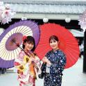 two women in kimonos are holding umbrellas