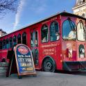 a red bus is parked next to a sign