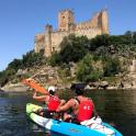 two people in a kayak on the water in front of a castle