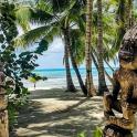 a couple of statues on a beach with palm trees