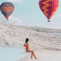 一名女子坐在海滩上，身边还有热气球