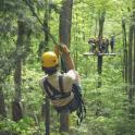 a man is hanging on a zip line in the forest