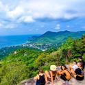 a group of people sitting on a rock overlooking the ocean