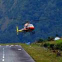 a red and yellow helicopter flying over a runway