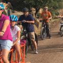 a group of people riding bikes on a dirt road