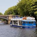 a blue and white boat on a river near a bridge