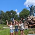 three girls are standing in front of a statue