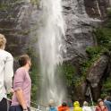 a group of people on a boat looking at a waterfall
