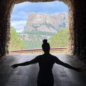 a person standing in a tunnel looking out at a mountain