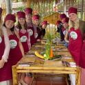 a group of people wearing red bonnets standing around a table