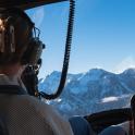 a person sitting in a seat looking out a window at mountains