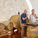two men standing in front of barrels in a room
