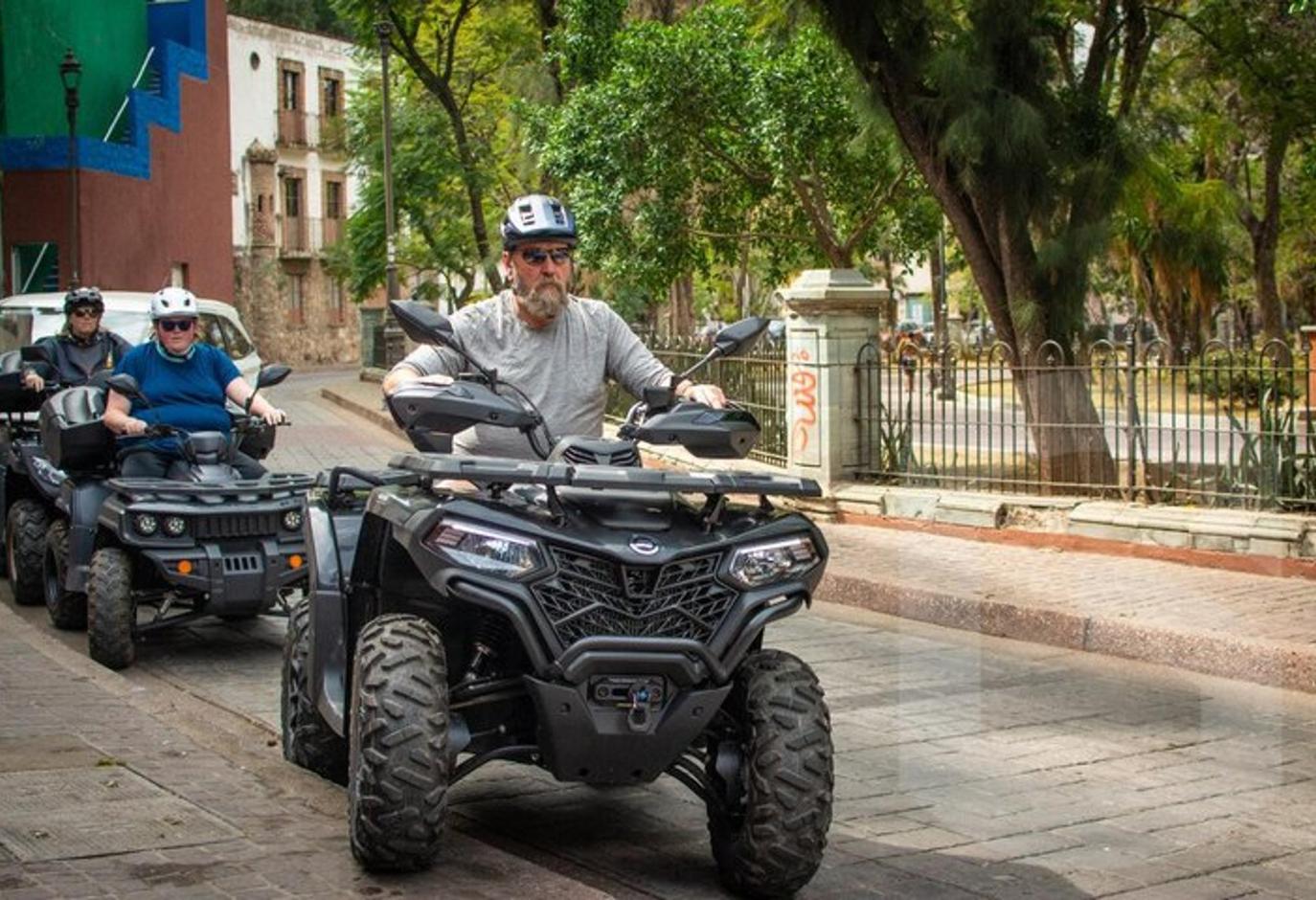 two people riding on atvs on a street