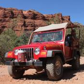 一辆红色吉普车沿着土路行驶