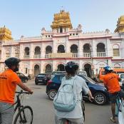 tři lidé na kolech před budovou