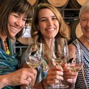 three women holding wine glasses in a wine cellar