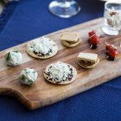 一块木砧板上放着四个小披萨