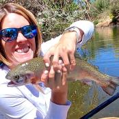 一名女子在水中抓着一条褐鳟鱼