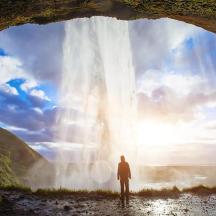 a man standing in front of a waterfall