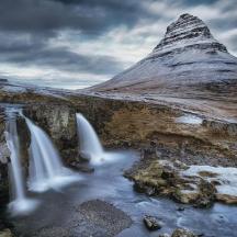 a mountain with a waterfall in front of a river