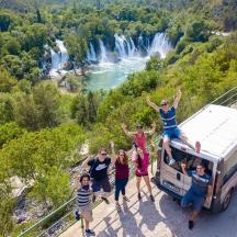 a group of people standing on a suspension bridge with a van