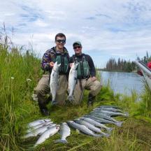 two men holding a bunch of fish next to a boat