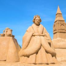a sandcastle with a statue of a man and a tower