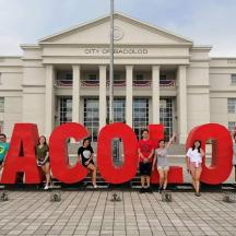 a group of people standing in front of a large sign in front of a building