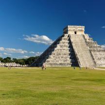 a pyramid in a field with people walking around it