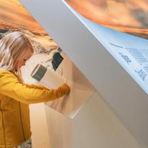 a young girl reading a book at an art exhibit