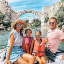 una família en una barca a l'aigua davant d'un pont