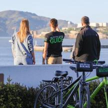 three people standing on a wall looking at the water