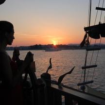 una mujer sentada en un barco mirando la puesta de sol