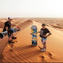two men are standing in the desert with skateboards