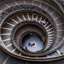 a spiral staircase in a building with people walking down it