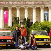 a group of people standing in front of two old cars