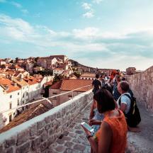 a group of people sitting on a wall looking at a city