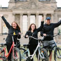 a group of three people on bikes in front of a building